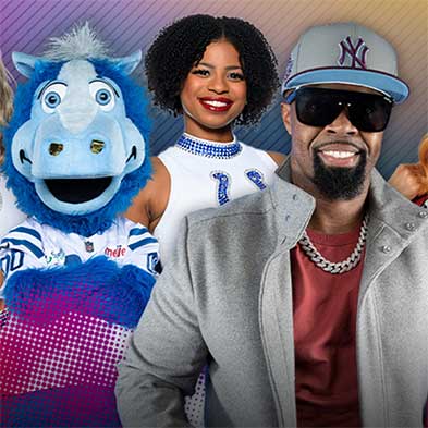 Artist, a mascot, and a cheerleader clustered together, smiling and posing for a photo.