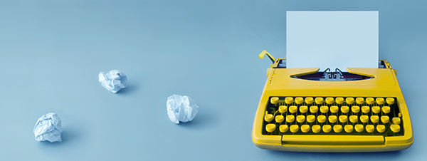 A typewriter with balled up papers next to it.